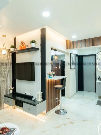 We designed this modern living room with a dark grey molded feature wall for a touch of drama. The space includes a breakfast counter that connects to the open kitchen, blending comfort and style.