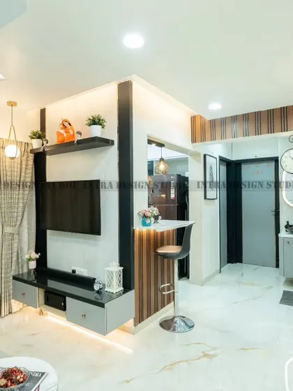 We designed this modern living room with a dark grey molded feature wall for a touch of drama. The space includes a breakfast counter that connects to the open kitchen, blending comfort and style.