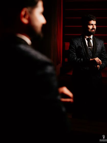 An artistic shot of the groom looking in the mirror, captured with dramatic lighting.