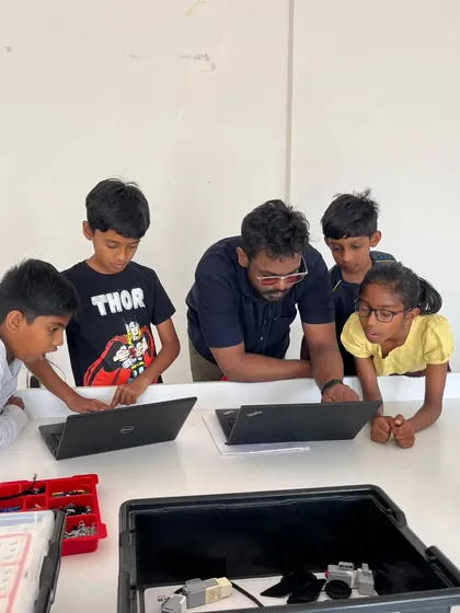 Our instructors are passionate about guiding the next generation of innovators. Here, an instructor works closely with a group of students during summer camp, helping them understand complex coding concepts on their laptops and bringing their LEGO robots to life.