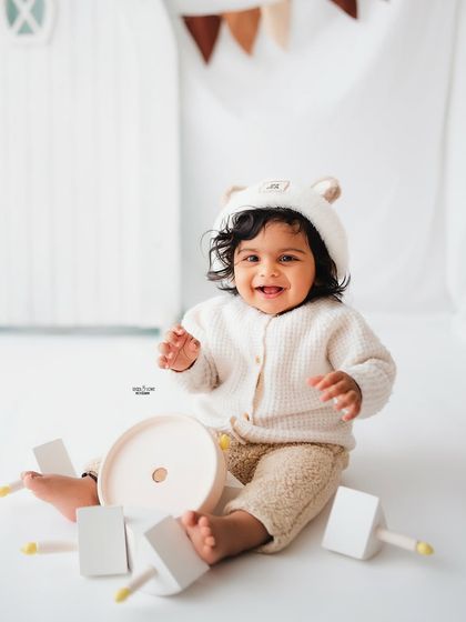 This little one is having a blast with his toys in this cute, neutral-toned teddy bear setup.