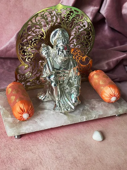 This silver-plated idol of Lord Hanuman, set against an ornate backdrop on a rose quartz base, exudes strength and devotion. It is a powerful symbol of faith and protection for your sacred space.