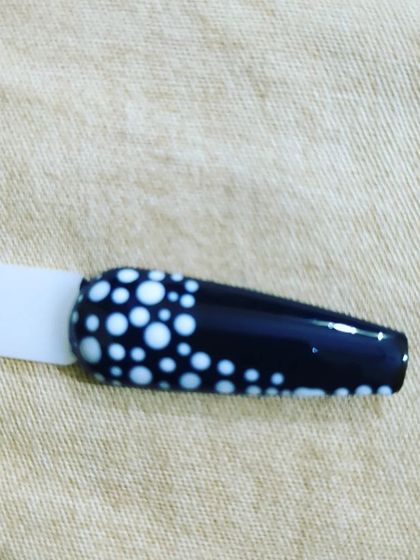 This sample shows a cascading dot pattern, with larger white dots at the base of the nail that get smaller towards the tip. It's a fun and dynamic design on a black base.