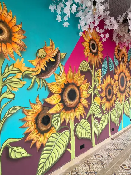 The sunflower wall mural seen from a distance, with decorative foliage hanging from the ceiling to complete the look.