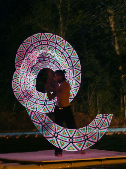 A flow artist manipulates LED poi to create complex geometric patterns in the dark. This blend of technology and art adds a modern, vibrant touch to the festival's nightlife.