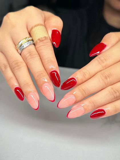 A modern and chic design with a mix of solid red and a negative space French tip on almond-shaped nails.
