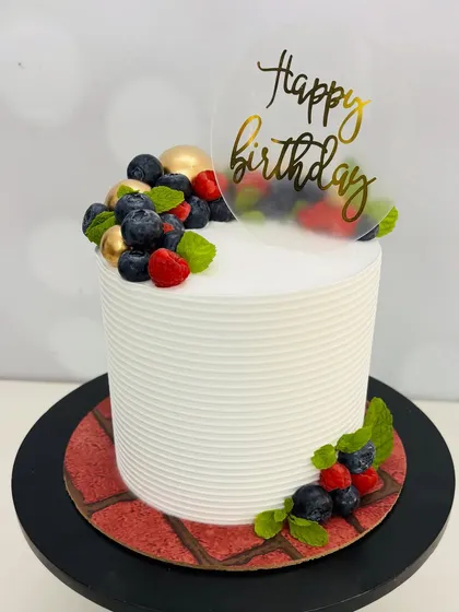 Simple, clean, and always in style. This tall white cake is adorned with fresh berries and mint leaves, making it a refreshing and elegant choice for any birthday celebration.