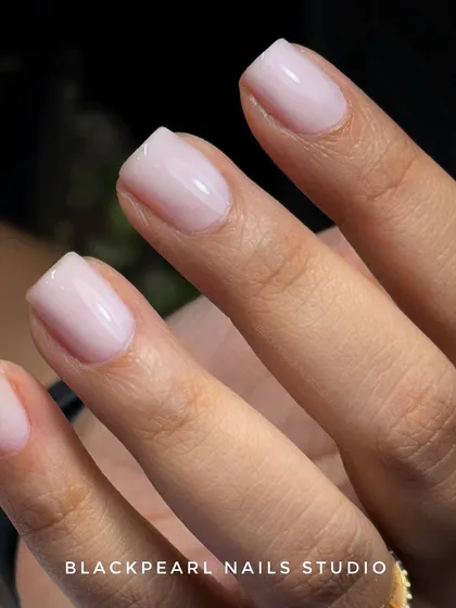 This is the "soap nails" look, a perfect example of the clean girl aesthetic achieved with a BIAB (Builder in a Bottle) overlay. It provides a sheer, glossy finish on natural nails, making them look healthy, strong, and impeccably clean. This service is ideal for clients who want to grow and strengthen their own nails.