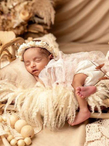 An angel sleeping in a boho-inspired setup. The natural textures of pampas grass and lace create a soft and dreamy atmosphere for this newborn portrait.