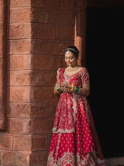 A beautiful bride in a red lehenga, captured in natural sunlight. The makeup is soft and romantic.