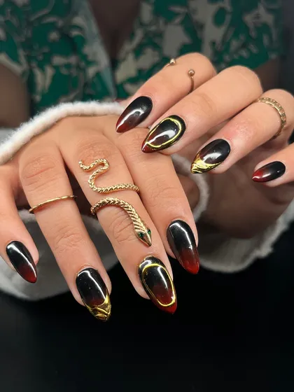 For those who love a darker aesthetic. This set features a dramatic black and red ombre effect on long almond nails, accented with bold, sculpted gold chrome details for a fierce and luxurious feel.