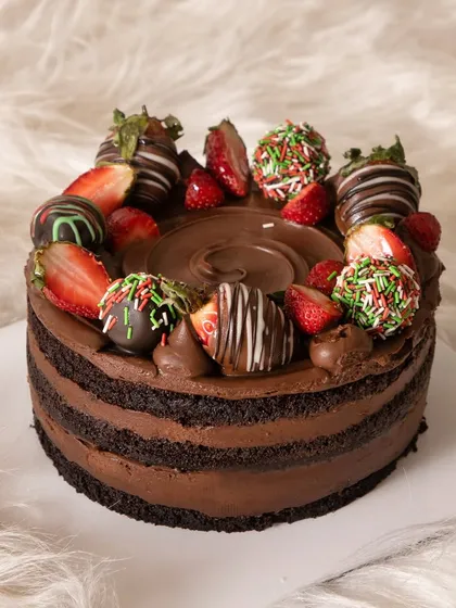 A simple yet stunning chocolate cake topped with fresh and chocolate-dipped strawberries, perfect for a festive or romantic occasion.