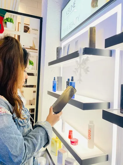 A client is seen here exploring my curated selection of premium hair and skin care products from brands like Keune and PH. I always help my clients choose the right products to maintain their glow at home.