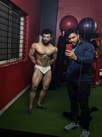 A classic physique pose in the gym. This shot highlights the quad sweep and upper body mass required for competitive bodybuilding.