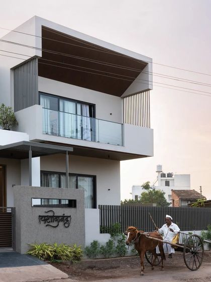 The facade of 'Yashodanand' is a study in modernism, with its clean white planes, deep-set windows, and cantilevered upper floor.