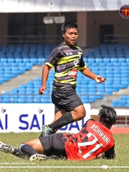 A defender makes a crucial slide tackle to stop an opponent's attack during a heated moment in a league game.
