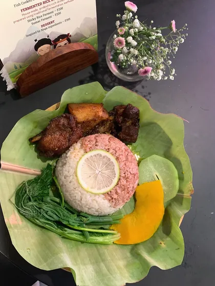 A beautifully arranged meal from our Tuluni festival celebration. Served on a banana leaf, it features smoked pork, rice, and fresh boiled greens, representing the harvest.