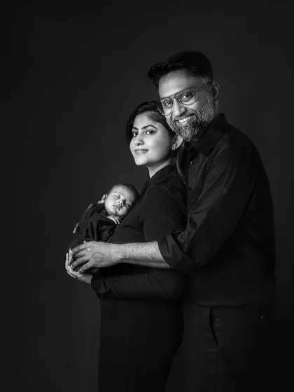 A classic family portrait in black and white. This image beautifully captures the beginning of a new family, with the parents holding their newborn baby close. It's a moment of pure love and connection.