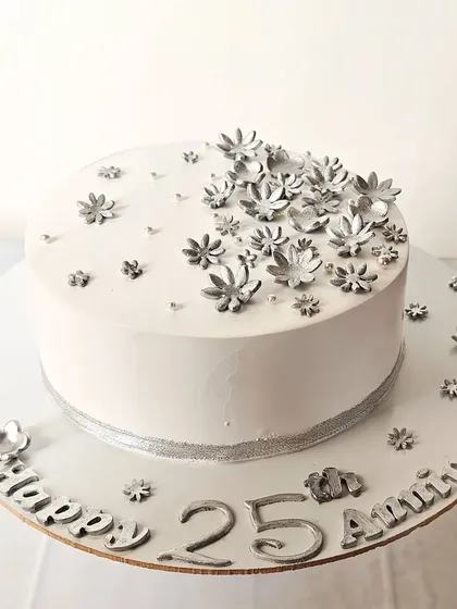 Cheers to 25 years with this beautiful silver anniversary cake. The all-white design is decorated with delicate silver flowers and a silver ribbon border.