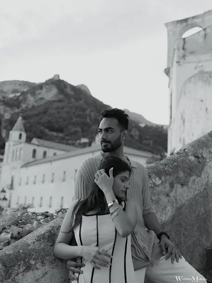 A moody black and white portrait from the Amalfi Coast, Italy. The historic architecture and the couple's contemplative pose give this image a timeless, cinematic quality.
