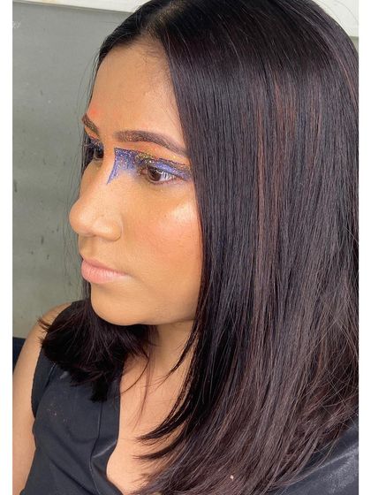 The profile view of this graphic editorial makeup shows the clean lines and the blend of orange and glitter eyeshadow. It's a look designed to be sharp and impactful on camera.