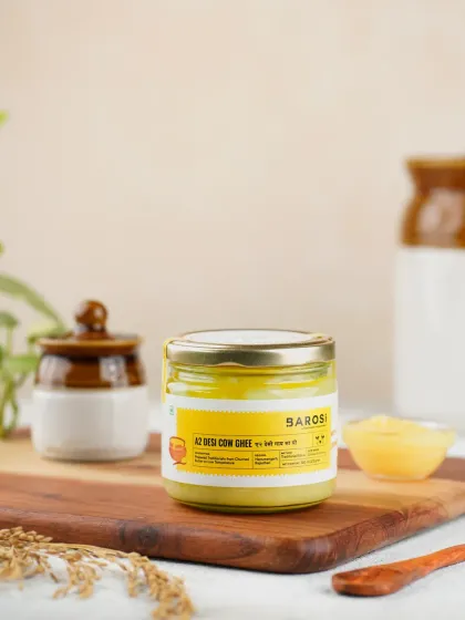 A clean and bright product shot of Barosi's A2 Desi Cow Ghee. The styling with traditional Indian pottery gives it an authentic, farm-fresh feel.