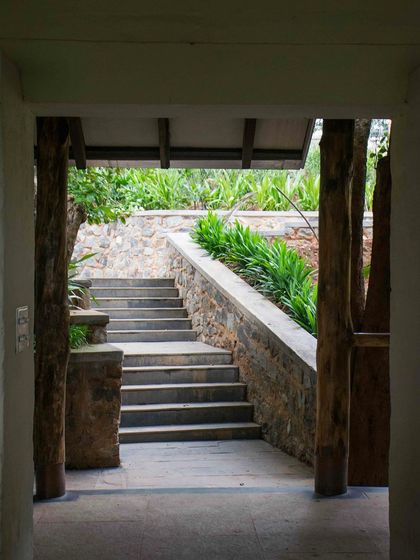 A view through a doorway at PLENTI House, looking out onto a flight of stone steps that navigate the steep terrain.