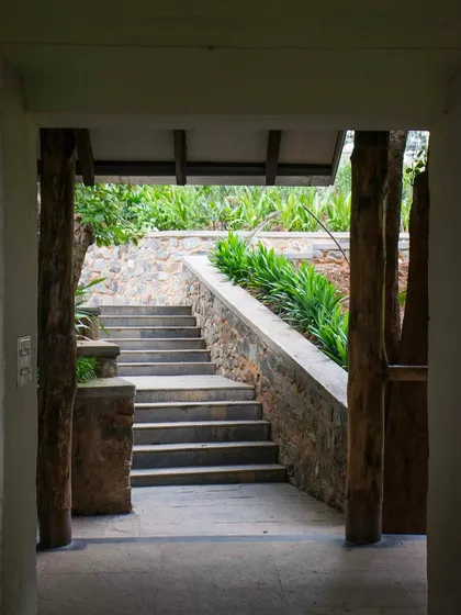 A view through a doorway at PLENTI House, looking out onto a flight of stone steps that navigate the steep terrain.