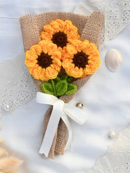 A rustic and charming bouquet of three crochet sunflowers, wrapped in burlap with a simple white ribbon. It's like holding a little bit of sunshine.