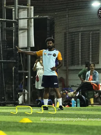 A coach sets up an agility drill, demonstrating his hands-on approach to every training session.