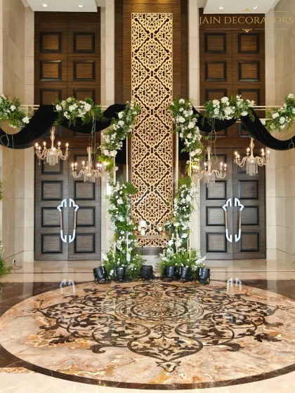 Grandeur begins at the door. For this ballroom entrance, I used a tall, intricate golden panel flanked by dramatic black drapes and white floral arrangements to create a statement of pure luxury.