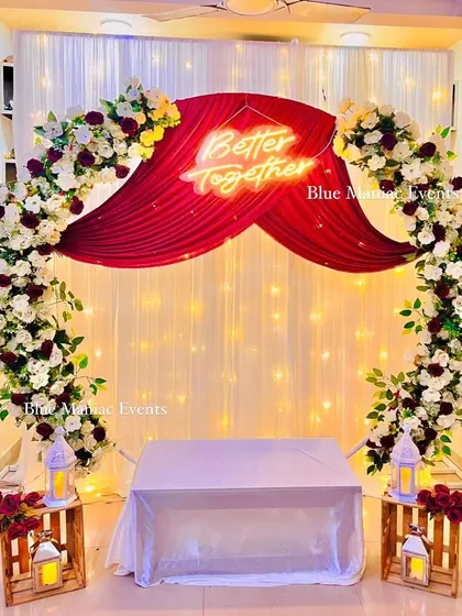 A complete view of the white and maroon engagement decoration. The circular arch, 'Better Together' sign, and rustic wooden crates with lanterns create a romantic and stylish look.