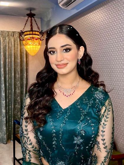 Elegant soft waves for a sangeet or cocktail party. The hair is styled to be sleek at the roots and flow into beautiful, uniform waves, with a few pearl studs for a touch of classic glamour.