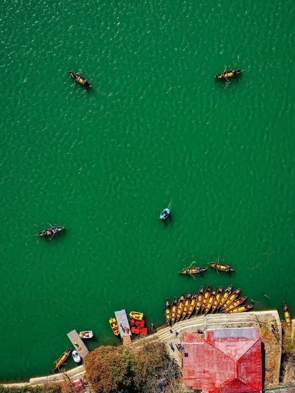 An aerial top-down perspective of the iconic Naini lake. This shot highlights the vibrant green of the water and the colorful boats, demonstrating a keen eye for composition and color that turns a familiar scene into a piece of art.