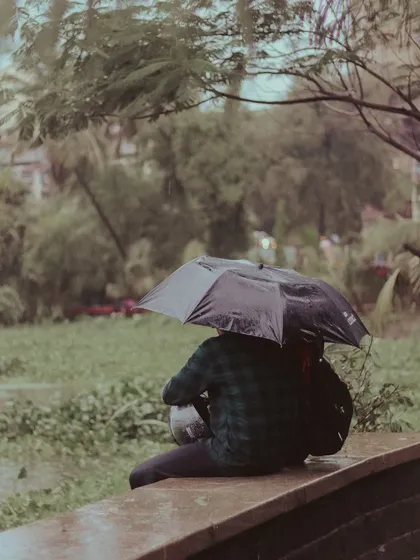 Someone finds a quiet spot to sit and watch the rain, protected by an umbrella. These are the peaceful, introspective moments that I love about the monsoon.