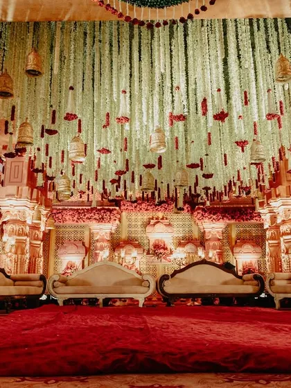 A duplicate of image 161, showing the beautiful interior of the mandap with its traditional seating and stunning ceiling of hanging flowers and bells.
