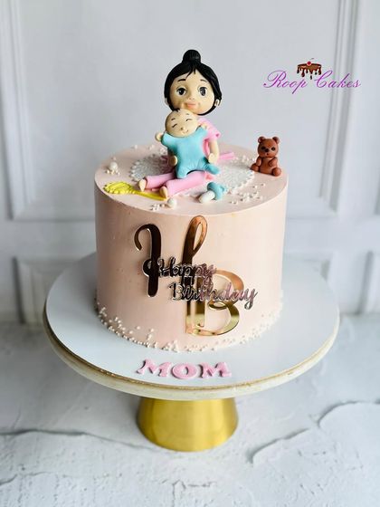 A special birthday cake for a new mom. This design features a handcrafted fondant figure of a mother holding her baby, celebrating her first birthday as a mom.