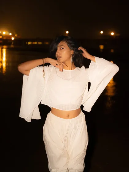This pose is dynamic and full of movement. The city lights in the background are blurred into soft bokeh, adding to the dreamy atmosphere.