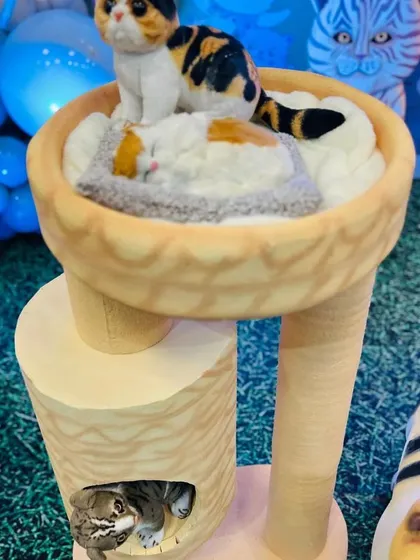 A close-up of the adorable cat figurines sleeping in a cat tree, part of our detailed cat-themed party decor.
