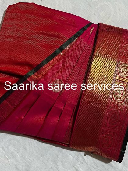 A red saree with a unique border design, pleated and ready. I can help you get any saree in your collection ready to wear.