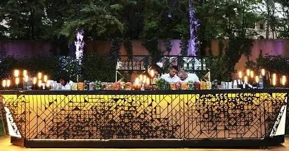 An elaborate geometric-patterned bar designed for a large wedding reception. This large-scale setup can accommodate multiple bartenders, ensuring fast service for a large number of guests without compromising on style.