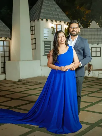 A fairytale setting for a pre-wedding night shoot. The couple stands in a beautifully lit miniature village, with the bride's royal blue gown adding a pop of vibrant color to the enchanting scene.