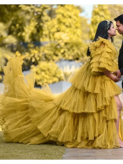 A romantic pose featuring our mustard yellow ruffled gown with a long, dramatic train. The high-low hemline adds a modern and fashionable touch to this maternity look.