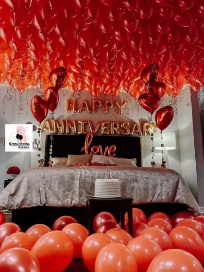 This is one of my signature romantic room decorations for an anniversary. The space is completely transformed with hundreds of red balloons on the ceiling, foil letter balloons spelling out the occasion, and a cake ready for a private celebration.