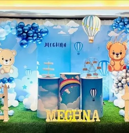 A cute teddy bear and hot air balloon theme. The sky-blue backdrop and cloud-like balloons create a dreamy and gentle atmosphere for a young child's party.