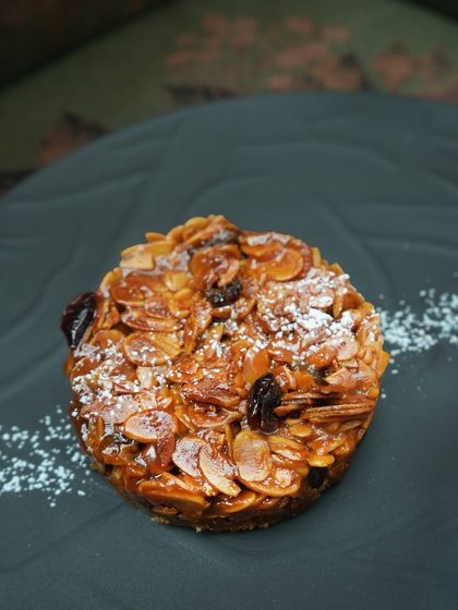 A close-up of our almond and fruit halwa tart, showing the rich texture of the caramelized nuts and dried fruit. It's a dessert that is both comforting and sophisticated.