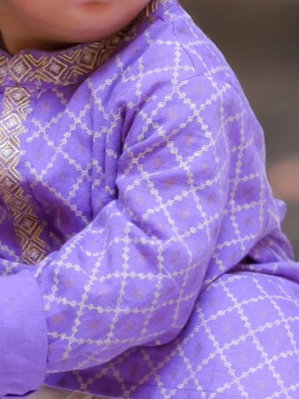 A detail shot of the beautiful embroidery on a child's traditional purple kurta, showcasing the special outfits worn on their big day.
