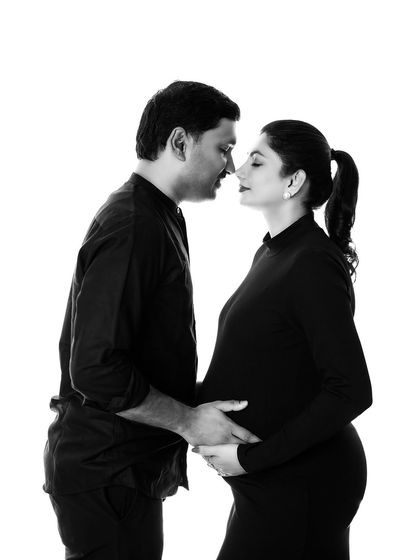 A classic black and white silhouette-style portrait. This artistic approach creates a timeless and intimate image, focusing on the couple's connection and the beautiful shape of the baby bump.