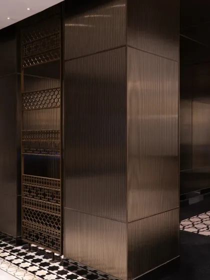 We integrated elements of Nepalese craftsmanship throughout the Soaltee lobby. These decorative metal screens feature intricate patterns inspired by traditional motifs, set within a contemporary framework of brushed bronze panels that define the space.