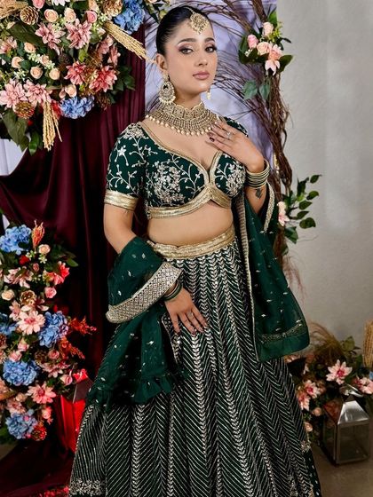 A full-length shot showcasing the beautiful fall of the emerald green lehenga, a perfect choice for a wedding guest.